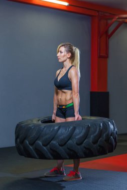 Kadın atlet dönüm büyük bir lastik ile çalışma dışarı uygun ve spor salonunda taşırlar. Crossfit kadın ile büyük lastik egzersiz