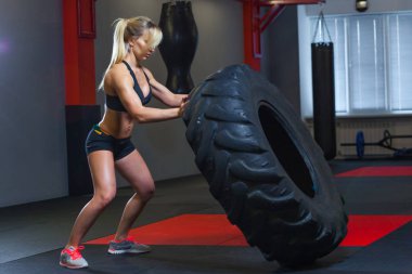 Kadın atlet dönüm büyük bir lastik ile çalışma dışarı uygun ve spor salonunda taşırlar. Crossfit kadın ile büyük lastik egzersiz
