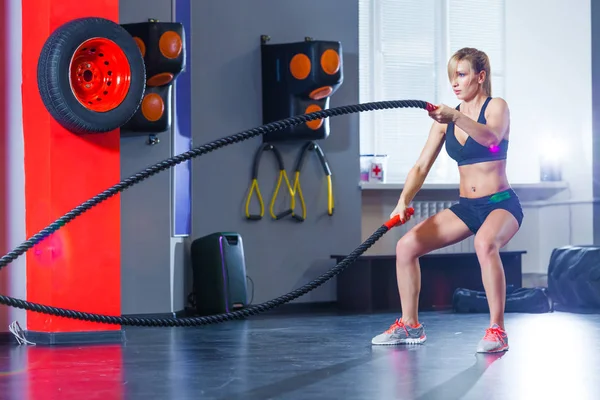 Mulher treinando com corda de batalha em cross fit ginásio — Fotografia de Stock