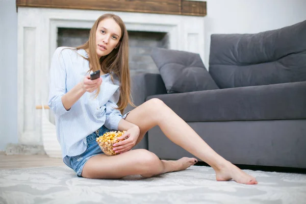 Linda jovem sorrindo mulher assistindo a um filme na cama e comer pipocas . — Fotografia de Stock