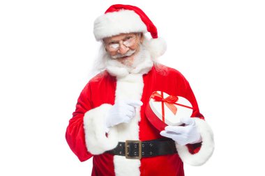 Noel. Noel Baba beyaz eldiven gülümseyen bir kırmızı ve beyaz kalp şeklinde hediye kutu kırmızı kurdele ile tutar. Beyaz arka plan üzerinde izole.