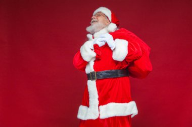 Noel. Tür ve beyaz eldiven yorgun Noel Baba'ya omzunun üzerinden hediyeler ile kırmızı bir çanta taşıyor. Kırmızı zemin üzerine izole.