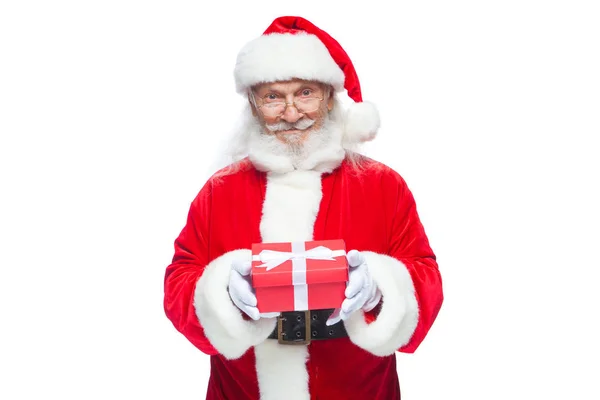 Jul. Ler Jultomten i vita handskar håller en röd presentbox med en rosett. Pekar på gåvan. Isolerad på vit bakgrund. — Stockfoto