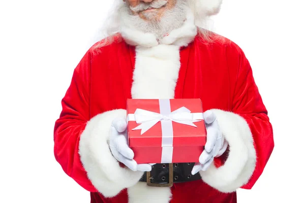 Christmas. Smiling Santa Claus in white gloves is holding a gift red box with a bow. Pointing at the gift. Isolated on white background. — Stock Photo, Image