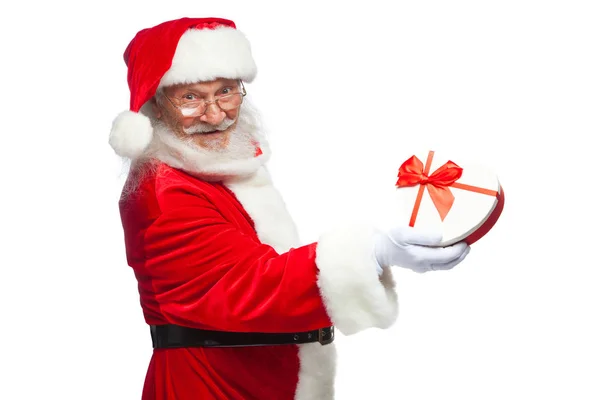Navidad. Santa Claus en guantes blancos sostiene una caja de regalo blanca en forma de corazón con una cinta roja. Aislado sobre fondo blanco. De cerca. — Foto de Stock