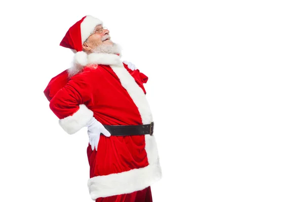 Weihnachten. Santa Claus leidet unter Rückenschmerzen und hält eine rote Tasche mit Geschenken auf dem Rücken. isoliert auf weißem Hintergrund. — Stockfoto