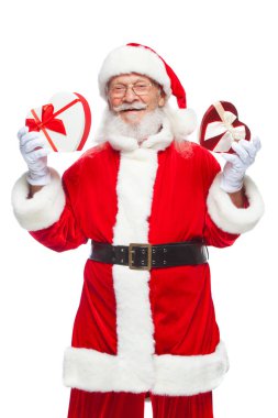 Noel. Noel Baba beyaz eldiven gülümseyen iki kırmızı ve beyaz kalp şeklinde hediye kutuları bir kurdele ile tutar. Cömert hediyeler kavramı. Beyaz arka plan üzerinde izole.