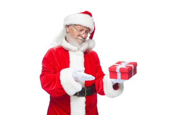 Navidad. Santa Claus sonriente con guantes blancos sostiene una caja roja de regalo con un lazo. Señalando el regalo. Aislado sobre fondo blanco . —  Fotos de Stock