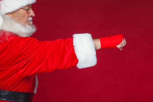 No Natal. Punho de Papai Noel com ligaduras vermelhas ferida para boxe. Kickboxing, boxe, karaté. Isolado em fundo vermelho . — Fotografia de Stock