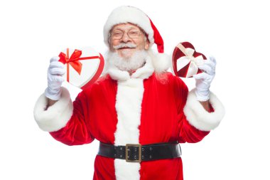 Noel. Noel Baba beyaz eldiven gülümseyen iki kırmızı ve beyaz kalp şeklinde hediye kutuları bir kurdele ile tutar. Cömert hediyeler kavramı. Beyaz arka plan üzerinde izole.