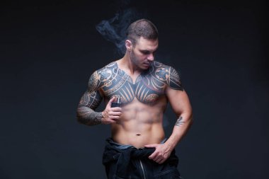 Bir kaslı çıplak gövde koyu arka plan üzerine dövmeli olan adam. ABS