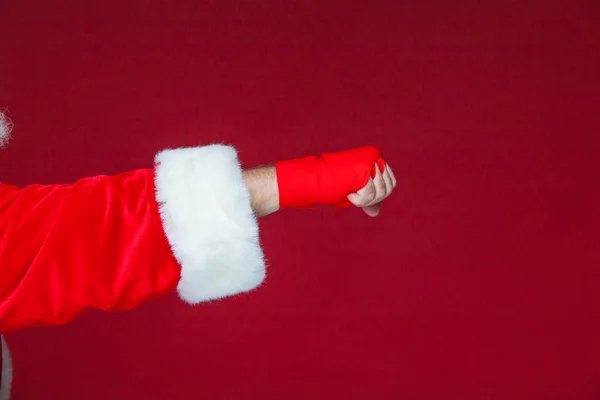 Weihnachten. Weihnachtsmann Faust mit roten Bandagen für das Boxen gewickelt. Kickboxen, Boxen, Karate. isoliert auf rotem Hintergrund. — Stockfoto