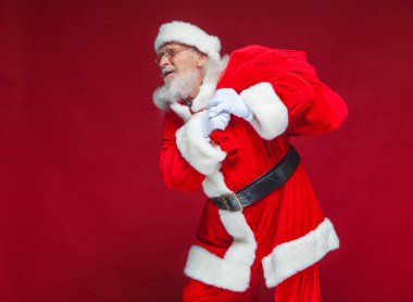 Noel. Tür ve beyaz eldiven yorgun Noel Baba'ya omzunun üzerinden hediyeler ile kırmızı bir çanta taşıyor. Kırmızı zemin üzerine izole.