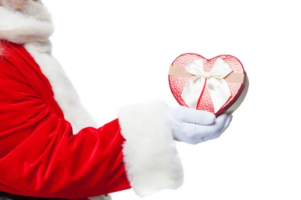 Weihnachten. Santa Claus in weißen Handschuhen hält eine rote herzförmige Geschenkschachtel mit einer weißen Schleife in der Hand. isoliert auf weißem Hintergrund. Nahaufnahme — Stockfoto