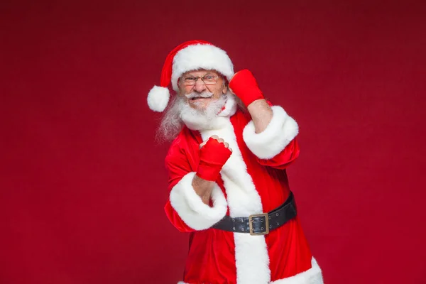 Weihnachten. Weihnachtsmann mit roten Bandagen, die sich um seine Hände wickeln, um Tritte zu imitieren. Kickboxen, Karate, Boxen. isoliert auf rotem Hintergrund. — Stockfoto