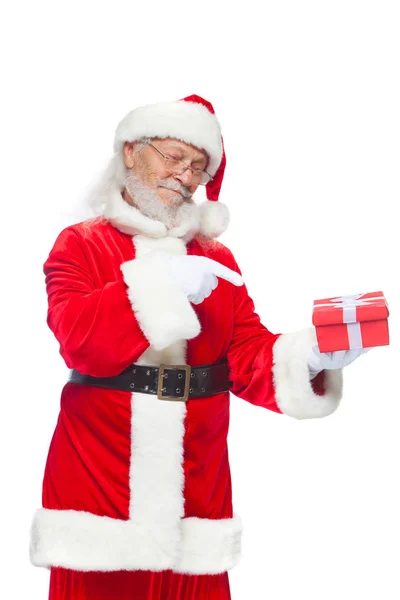 No Natal. Sorrindo Papai Noel em luvas brancas está segurando uma caixa vermelha de presente com um arco. Apontando para o presente. Isolado sobre fundo branco . — Fotografia de Stock