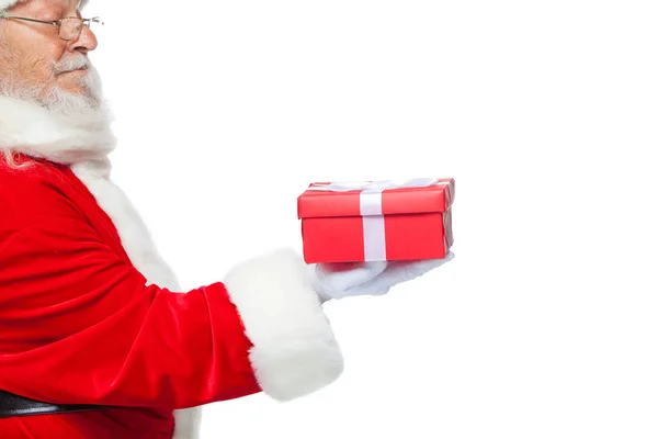 Weihnachten. Lächelnder Weihnachtsmann in weißen Handschuhen hält eine rote Geschenkschachtel mit Schleife in der Hand. zeigt auf das Geschenk. isoliert auf weißem Hintergrund. Nahaufnahme — Stockfoto