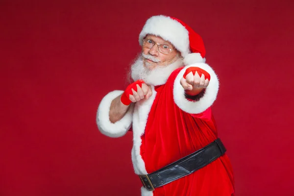 Boże Narodzenie. Santa Claus czerwony bandaże rany na rękach do boksu imituje kopnięć. Kickboxing, karate, boks. Na białym tle na czerwonym tle. — Zdjęcie stockowe