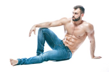 vücut geliştirmeci poz. Güzel sportif adam erkek güç. Fitness mavi kot pantolon kaslı. izole beyaz arka plan üzerinde. yere oturur