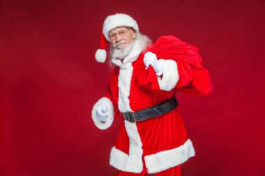 Noel. Tür ve beyaz eldiven yorgun Noel Baba'ya omzunun üzerinden hediyeler ile kırmızı bir çanta taşıyor. Kırmızı zemin üzerine izole.