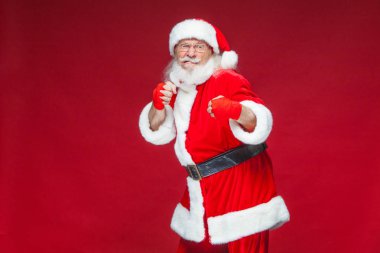 Noel. Noel Baba kırmızı bandaj boks için ellerinde yara ile başladı taklit ediyor. Kickboks, karate, boks. Kırmızı zemin üzerine izole.