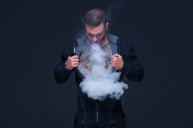 Vaper. Dövmeli bir kaslı çıplak gövde adamla koyu arka plan üzerinde elektronik sigara duman