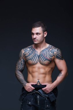 Bir kaslı çıplak gövde koyu arka plan üzerine dövmeli olan adam. ABS