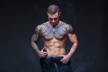 Vaper. Dövmeli bir kaslı çıplak gövde adamla koyu arka plan üzerinde elektronik sigara duman