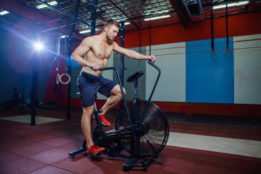 Spor salonunda egzersiz bisikleti kullanan genç adam uygun. Kardiyo egzersiz spor eğitim çapraz için hava bisiklet kullanarak fitness erkek.