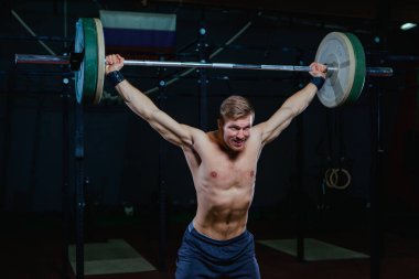 Yakışıklı bir atlet portresi. Atlet halter başının üzerine yükseltir. çekim koyu tonda. Çapraz tarzı uygun, deadlift