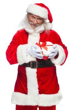 Noel. Noel Baba beyaz eldiven gülümseyen bir kırmızı ve beyaz kalp şeklinde hediye kutu kırmızı kurdele ile tutar. Beyaz arka plan üzerinde izole.