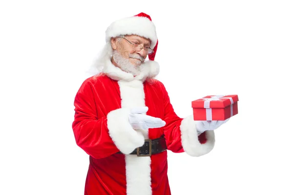 Weihnachten. Lächelnder Weihnachtsmann in weißen Handschuhen hält eine rote Geschenkschachtel mit Schleife in der Hand. zeigt auf das Geschenk. isoliert auf weißem Hintergrund. — Stockfoto