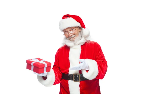 Weihnachten. Lächelnder Weihnachtsmann in weißen Handschuhen hält eine rote Geschenkschachtel mit Schleife in der Hand. zeigt auf das Geschenk. isoliert auf weißem Hintergrund. — Stockfoto