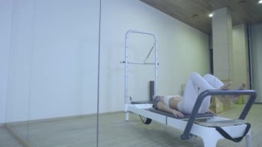 Pilates. Spor salonunda reformcu germe egzersiz pratik beyaz giysili bir kadın. tüm seri numarası 01234567890001.