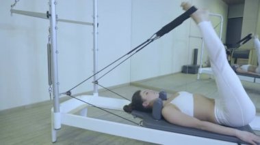 Pilates. Spor salonunda reformcu germe egzersiz pratik beyaz giysili bir kadın. tüm seri numarası 01234567890001.