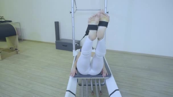 Pilates. Vrouw in witte kleren, stretching oefening op hervormer in sportschool te beoefenen. alle series door nummer 01234567890001. — Stockvideo