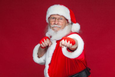 Noel. Noel Baba kırmızı bandaj boks için ellerinde yara ile başladı taklit ediyor. Kickboks, karate, boks. Kırmızı zemin üzerine izole.