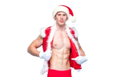 Seksi Noel Baba. Noel Baba şapkası takan genç kaslı adam kaslarını gösteriyor. Beyaz arkaplanda izole.