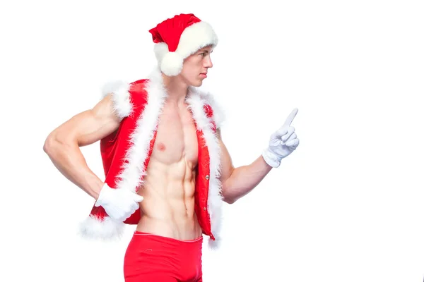 Babbo Natale sexy che punta nel segno bianco vuoto. Il giovane uomo muscoloso che indossa il cappello di Babbo Natale dimostra i suoi muscoli. Isolato su sfondo bianco . — Foto Stock