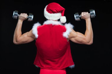 Tatiller ve kutlamalar, yeni yıl, yılbaşı, spor, vücut geliştirme, sağlıklı yaşam - kas yakışıklı Noel Baba. siyah bir arka plan üzerinde dumbbells ile. Beyaz arka plan üzerinde izole.