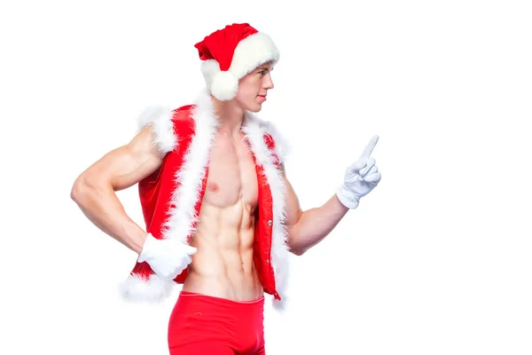 Sexy Santa Claus, wskazując w biały znak puste. Młody człowiek mięśni noszenie czapki Mikołajów wykazać jego mięśnie. Na białym tle. — Zdjęcie stockowe