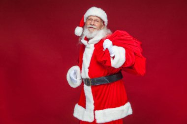 Noel. Tür ve beyaz eldiven yorgun Noel Baba'ya omzunun üzerinden hediyeler ile kırmızı bir çanta taşıyor. Kırmızı zemin üzerine izole.