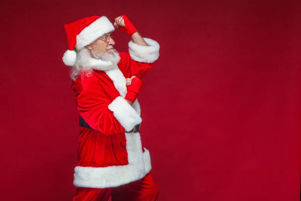 Weihnachten. Weihnachtsmann mit roten Bandagen, die sich um seine Hände wickeln, um Tritte zu imitieren. Kickboxen, Karate, Boxen. isoliert auf rotem Hintergrund. — Stockfoto