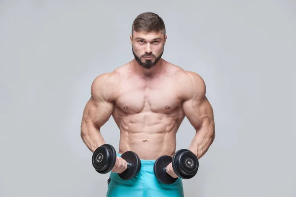 Muskulöser Bodybuilder, der Übungen mit der Hantel vor grauem Hintergrund macht — Stockfoto