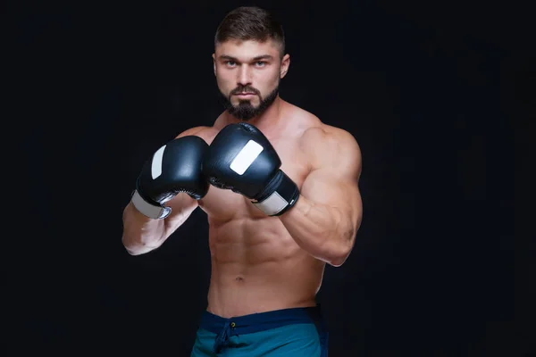 Silný svalnatý boxer v černých Boxerské rukavice. Izolované na černém pozadí. — Stock fotografie