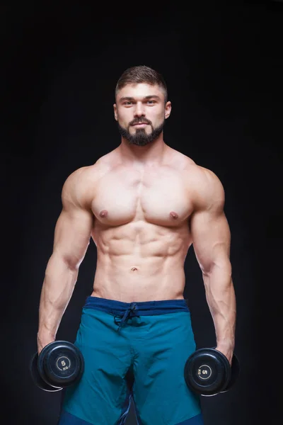 Gespierde bodybuilder man doen oefeningen met dumbbell op zwarte achtergrond — Stockfoto