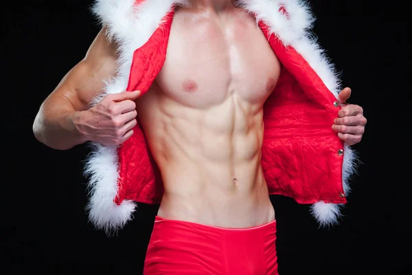 Sexy Père Noël. Jeune homme musclé portant le chapeau du Père Noël démontrer ses muscles. Isolé sur fond noir. — Photo