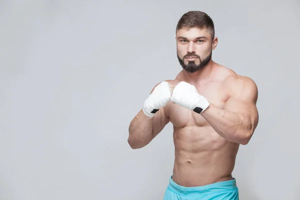 Muscular Fighter kickbox con fasciature bianche sullo sfondo grigio — Foto Stock