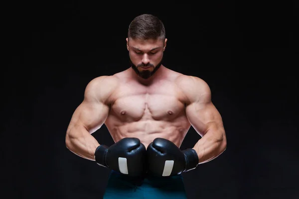 Сильный мускулистый боксер в черных боксерских перчатках. Изолированный на черном фоне . — стоковое фото