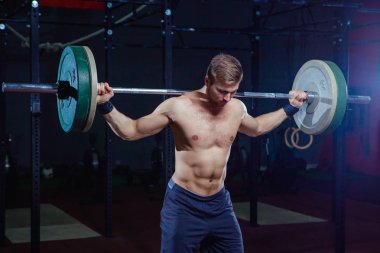 Yakışıklı bir atlet portresi. Atlet halter başının üzerine yükseltir. çekim koyu tonda. Çapraz tarzı uygun, deadlift